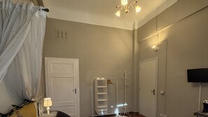 A hotel room with a bed, a bedside lamp, a wardrobe, a television, and a chandelier. - Guest Housa Santa Giustina (Lucca)