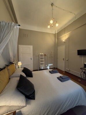 A hotel room with a bed, a bedside lamp, a wardrobe, a television, and a chandelier. - Guest Housa Santa Giustina (Lucca)