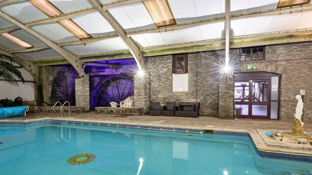 An indoor swimming pool with stone walls, a covered roof, and a statue near the edge. - Trimstone Manor - Granary Cottage (Woolacombe)