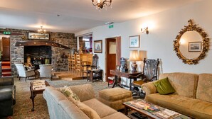 A cozy hotel lobby with a stone fireplace, comfortable seating, and a chandelier. - Trimstone Manor - Granary Cottage (Woolacombe)