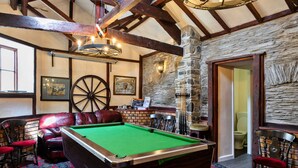 A pool table in a room with stone walls, wooden beams, and a red carpet. - Trimstone Manor - Granary Cottage (Woolacombe)