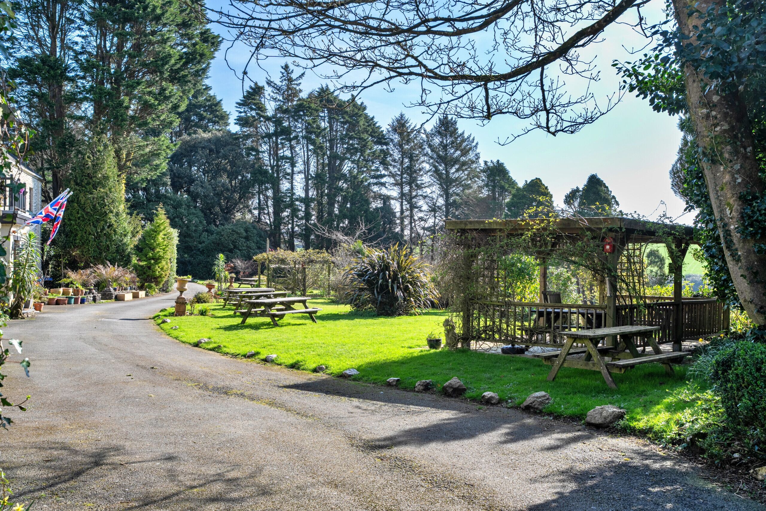 A park with picnic tables, a wooden gazebo, and a flag.