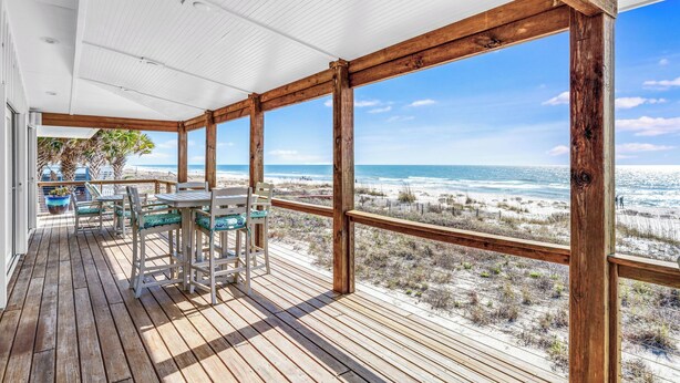 A wooden deck with a table and chairs, overlooking a beach. - Getaway Beach Front, St. George Island Private 4  Bedroom Home (St. George Island)