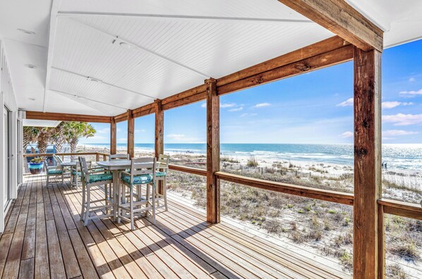 A wooden deck with a table and chairs, overlooking a beach. - Getaway Beach Front, St. George Island Private 4  Bedroom Home (St. George Island)