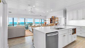 A spacious kitchen with a large island, white cabinetry, and a view of the ocean. - Getaway Beach Front, St. George Island Private 4  Bedroom Home (St. George Island)