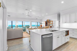 A spacious kitchen with a large island, white cabinetry, and a view of the ocean. - Getaway Beach Front, St. George Island Private 4  Bedroom Home (St. George Island)