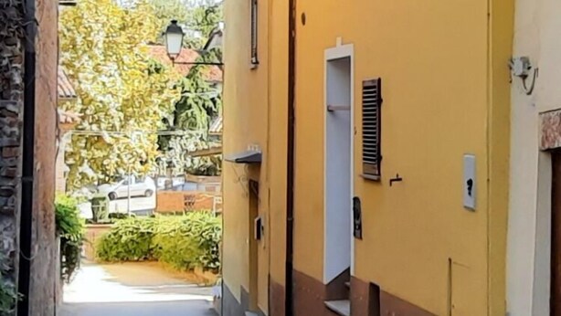 A narrow street with a yellow building, a street lamp, and a door. - Palazzo Peisoire - Appartamento con garage per E-Bike (Montaldo Torinese)
