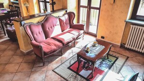 A room with a red upholstered sofa, a wooden coffee table, and a tiled floor. - Palazzo Peisoire - Appartamento con garage per E-Bike (Montaldo Torinese)