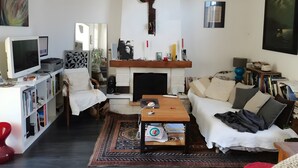 Ein Wohnzimmer mit Kamin, Fernseher, Bücherregal und einer Couch.