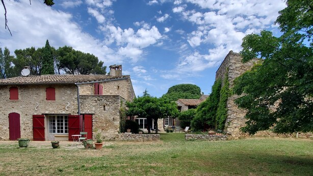 A stone building with red shutters, a small outdoor seating area, and a garden. - Rent house very beautiful mas provençal south Luberon - 10 beds (Mérindol)