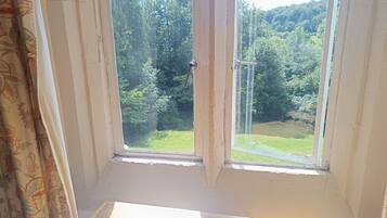 A room with a window overlooking a forested area.