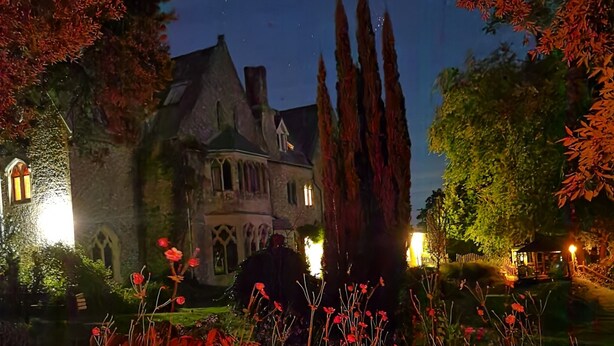 A historic building with a prominent tower, surrounded by a well-maintained garden with flowering plants. - Monkton Wyld Court (Bridport)