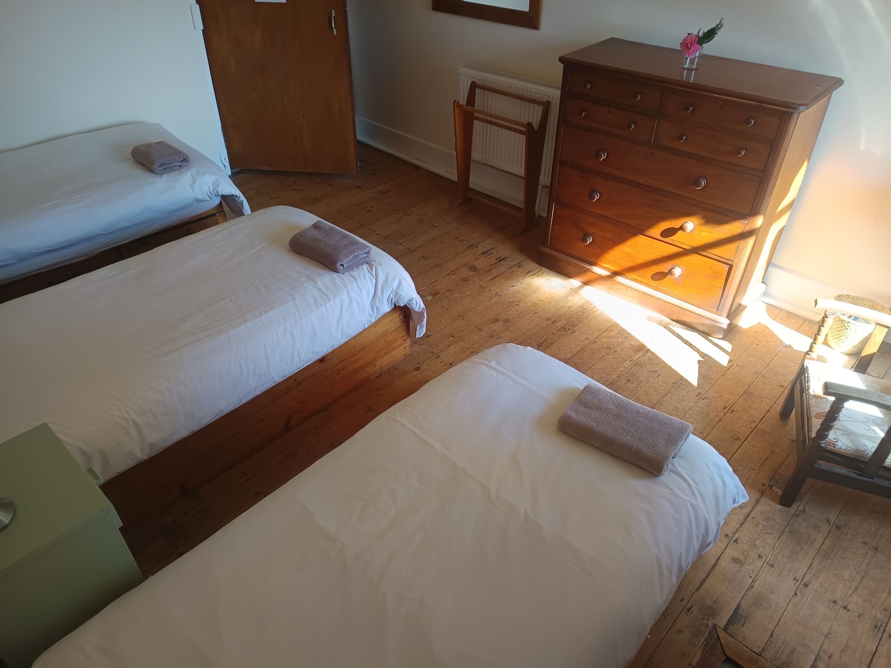 A room with two beds, a wooden dresser, and a radiator.