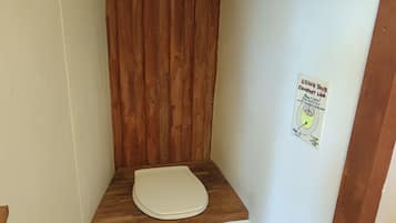 Un baño pequeño con un banco de madera, un inodoro y un cartel que indica usar el váter.