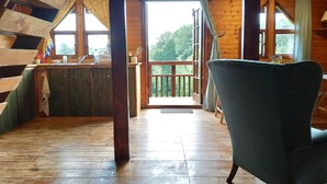 A wooden cabin with a balcony, a kitchen area, and a chair. - Monkton Wyld Court (Bridport)