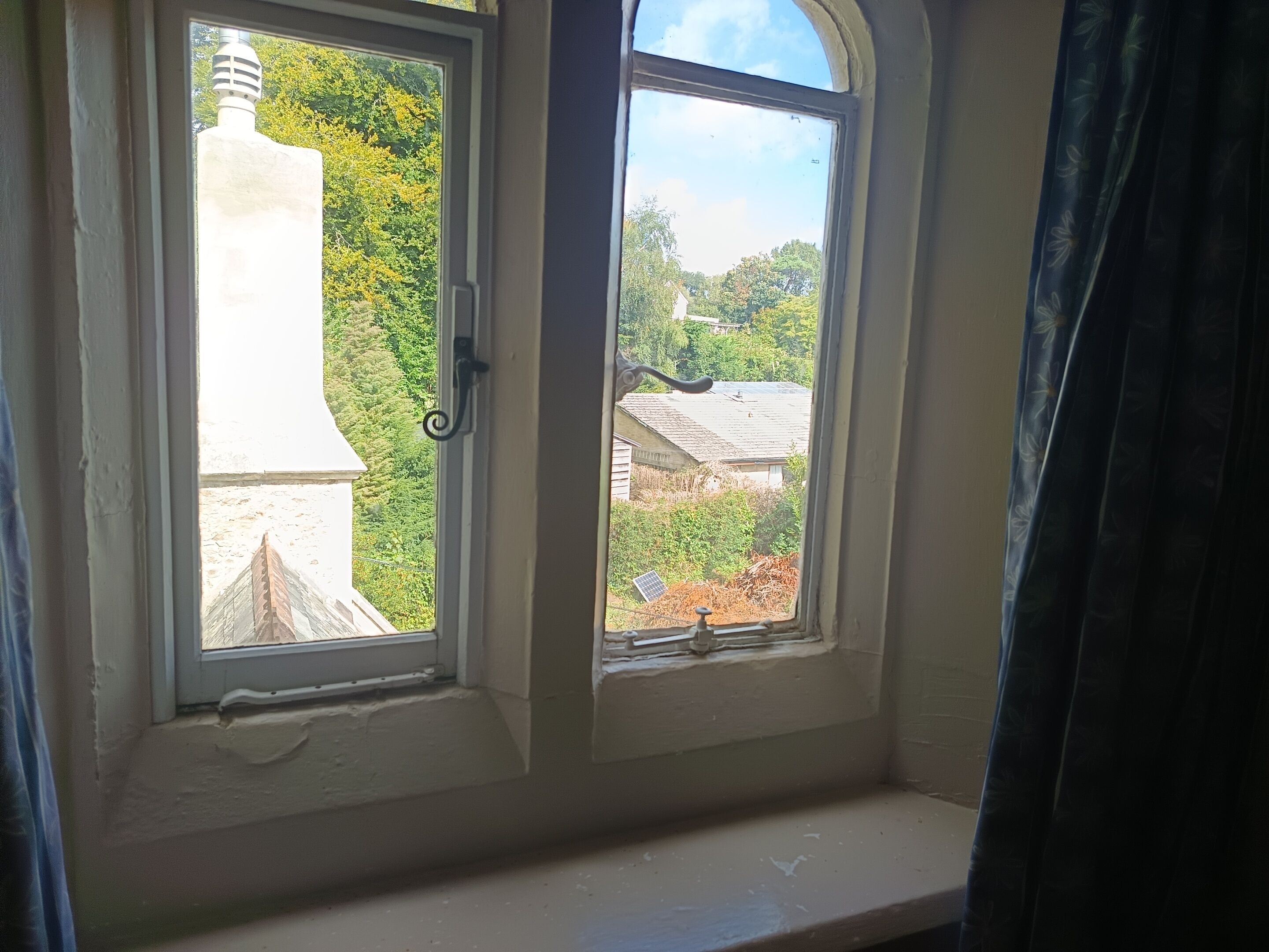Une fenêtre donnant sur un bâtiment et sur de la verdure.