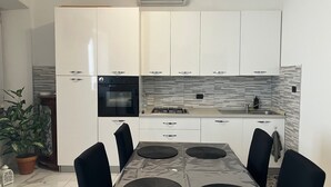 Eine moderne Küche mit weißen Schränken, einem schwarzen Backofen, einem Gasherd und einer gefliesten Spritzschutzwand.