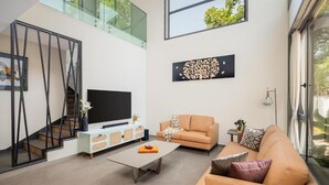 A modern living room with a sofa, coffee table, TV, and artwork. - Cloud 7 by ELIVAAS Luxurious 4 BHK Villa (Vagator)