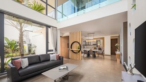 A modern living room with a sofa, coffee table, and a dining area with chairs and a table. - Cloud 7 by ELIVAAS Luxurious 4 BHK Villa (Vagator)