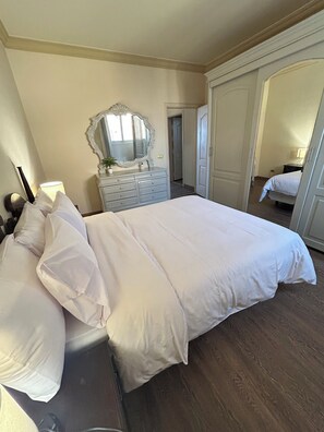 Ein Schlafzimmer mit einem großen Bett, einem Schminktisch, einem Spiegel und einem Kleiderschrank.