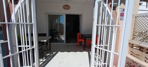 A view through a gated entrance to a room with a table and chairs, a sliding glass door, and a wicker ceiling light. - Beachfront Flat With Spectacular sea Views (Roquetas de Mar)
