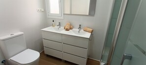 A bathroom with a toilet, a sink with a mirror, and a glass shower enclosure. - Beachfront Flat With Spectacular sea Views (Roquetas de Mar)