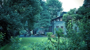 Een groot huis, omringd door dichte bomen en een verzorgd gazon.