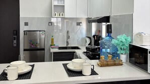 Eine moderne Küche mit weißen Schränken, einem Edelstahlkühlschrank, einer Spüle und einem Essbereich mit Tisch für zwei Personen.