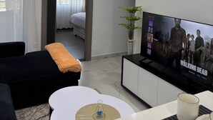 Ein modernes Wohnzimmer mit Flachbildfernseher, einer Couch, einem Couchtisch und einem Essbereich.