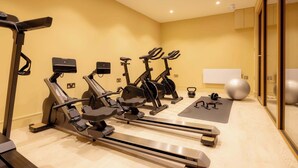 Ein Fitnessraum mit stationären Fahrrädern, einem Rudergerät und Trainingsbällen.