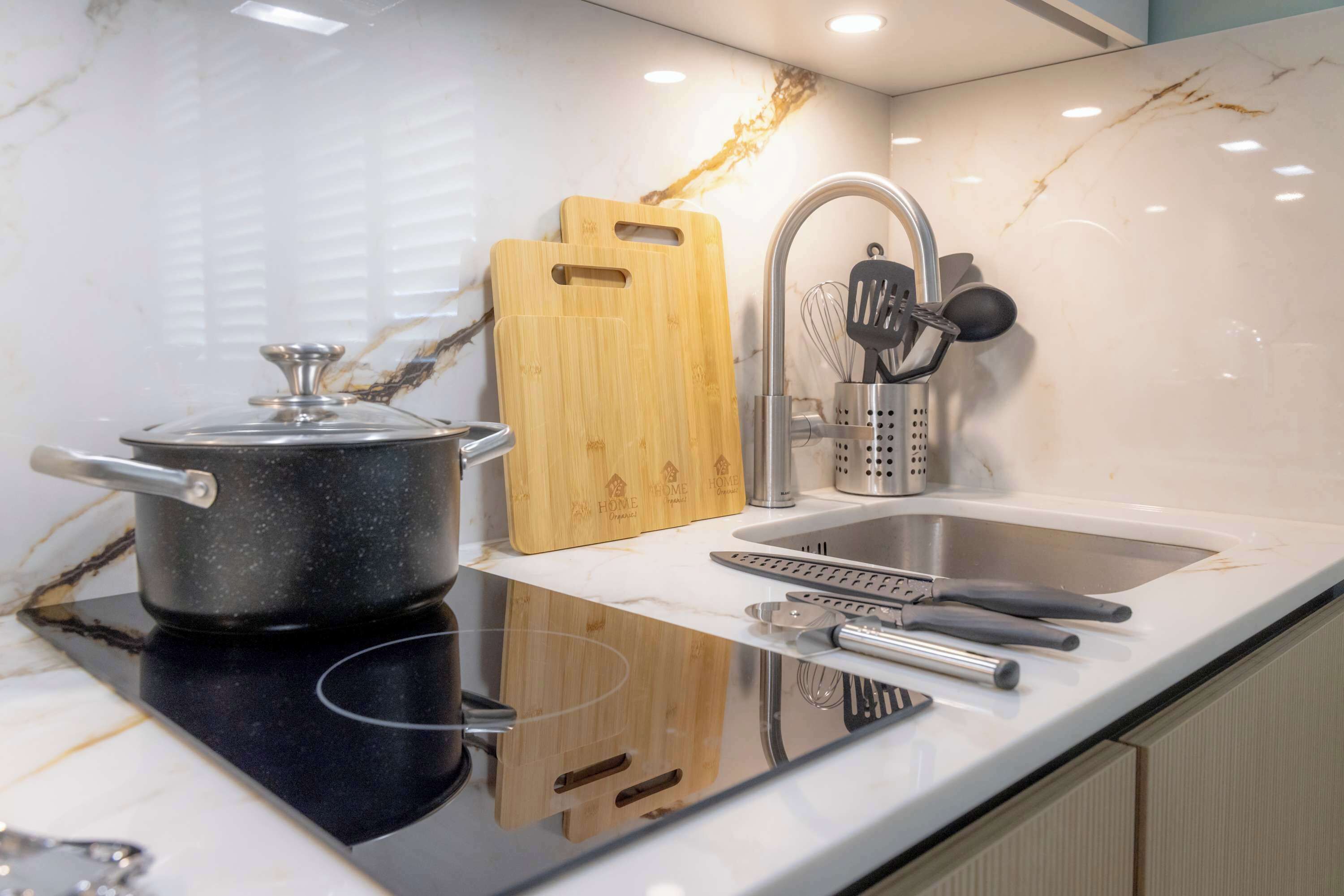 A kitchen with a stove, sink, cutting board, and utensils.