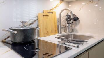 A kitchen with a stove, sink, cutting board, and utensils.