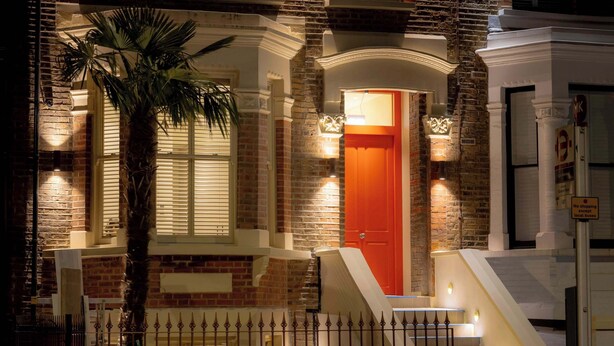 A brick building with a red door, a palm tree, and a staircase. - Deluxe Studio 9 at The Orange Door Little Venice (Greater London)