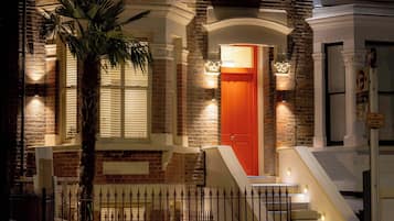 A brick building with a red door, a palm tree, and a staircase.