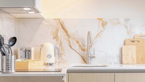 Una cocina moderna con salpicadero de mármol, un lavamanos de acero inoxidable y tablas de cortar de madera.