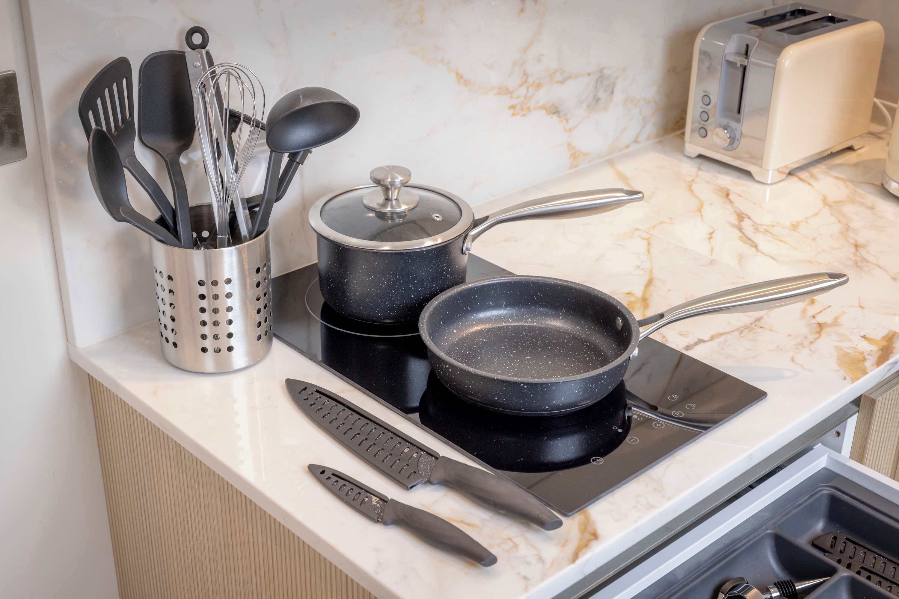 Une cuisine équipée d’une cuisinière, de casseroles, d’un grille-pain et d’un porte-ustensiles.