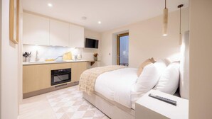 Quarto moderno com cama, mesa de cabeceira e controle remoto.