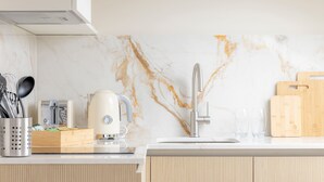Une cuisine avec un dosseret en marbre, une machine à café, un évier et des planches à découper en bois.