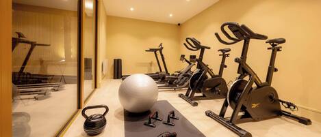 A gym with exercise equipment, a large exercise ball, and a yoga mat.
