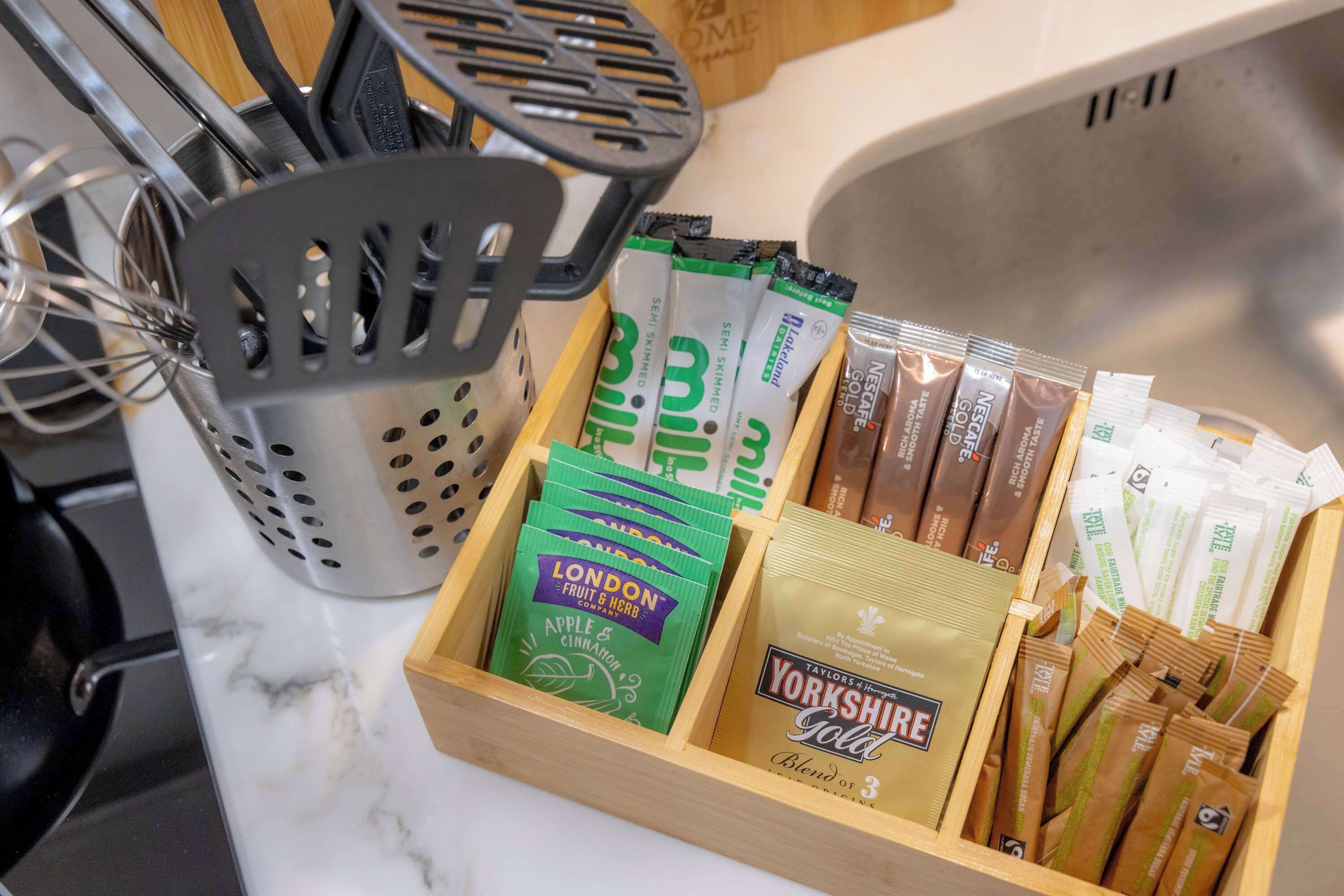 Une boîte en bois contenant des sachets de thé et un fouet.