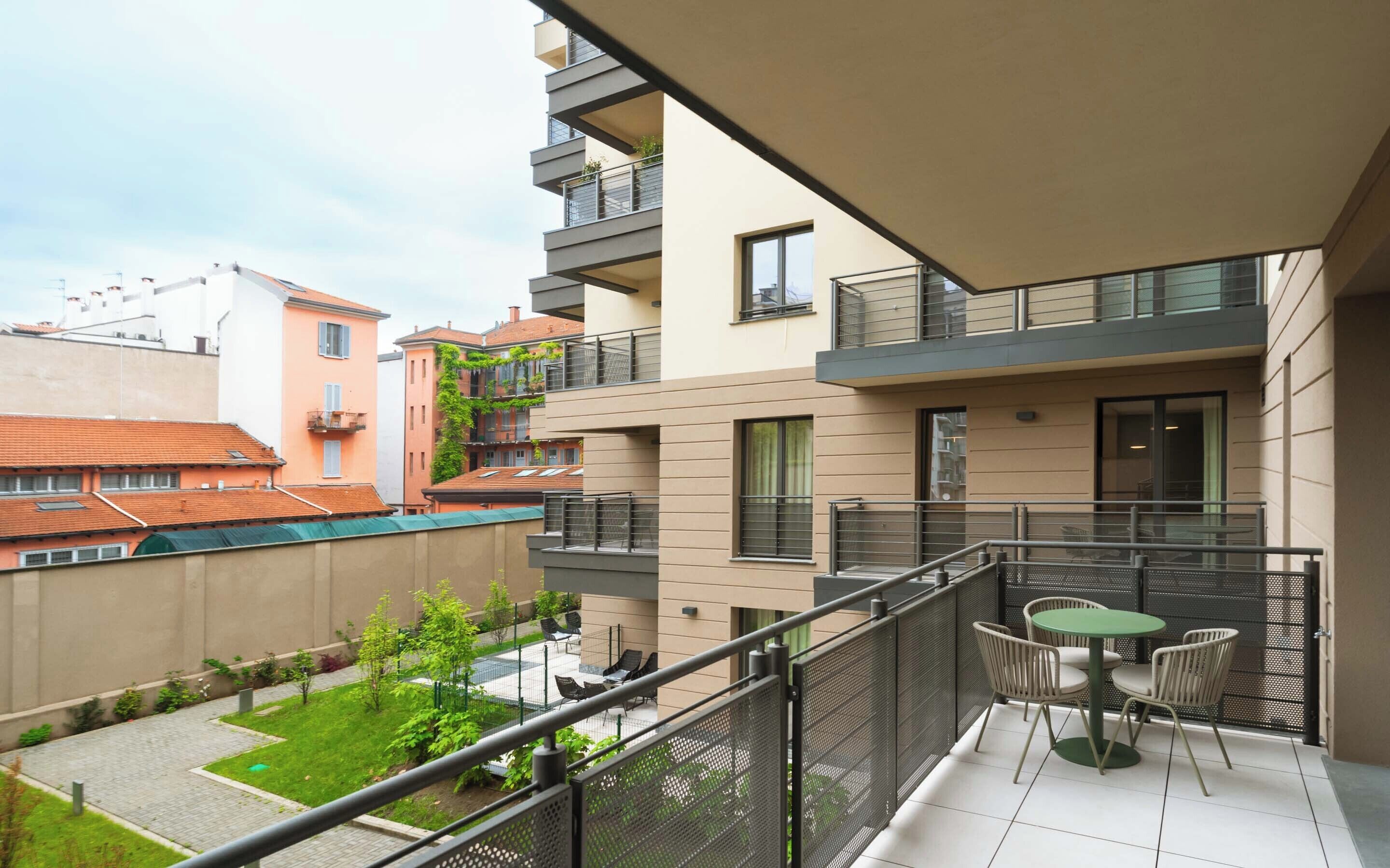 A modern apartment with a balcony, outdoor seating, and a view of neighboring buildings.