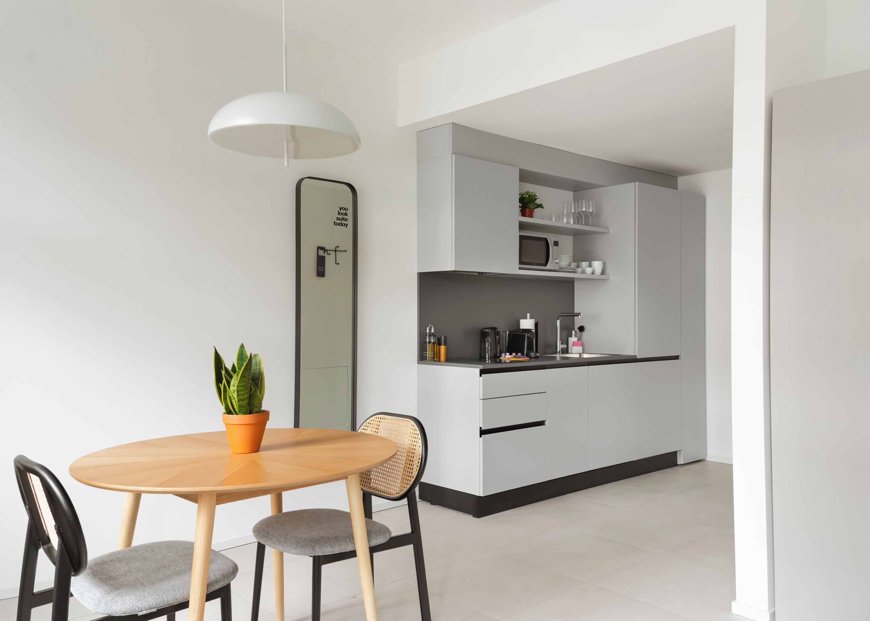 A modern kitchen with a microwave, coffee maker, and cabinets.
