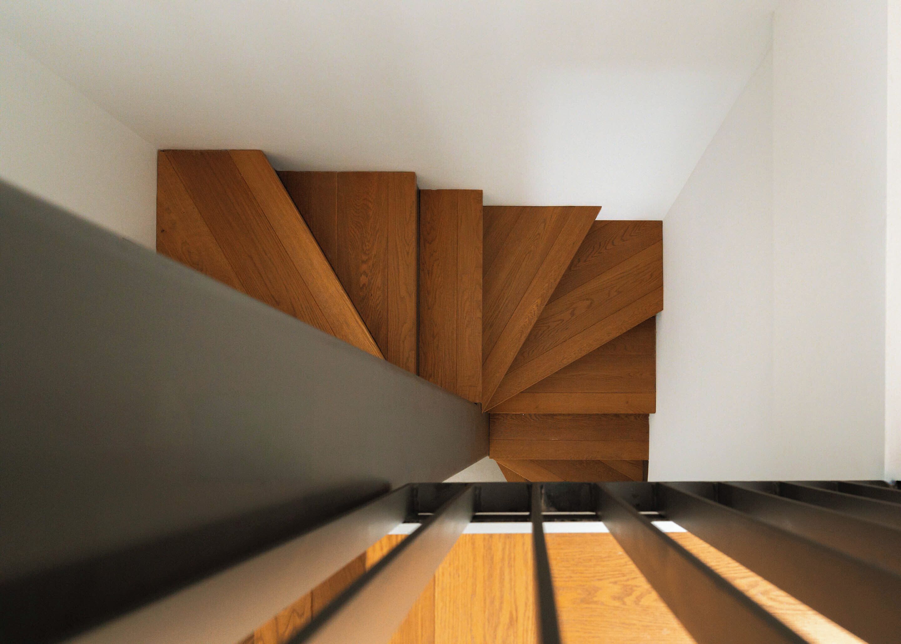 A modern staircase with wooden steps and a black handrail.