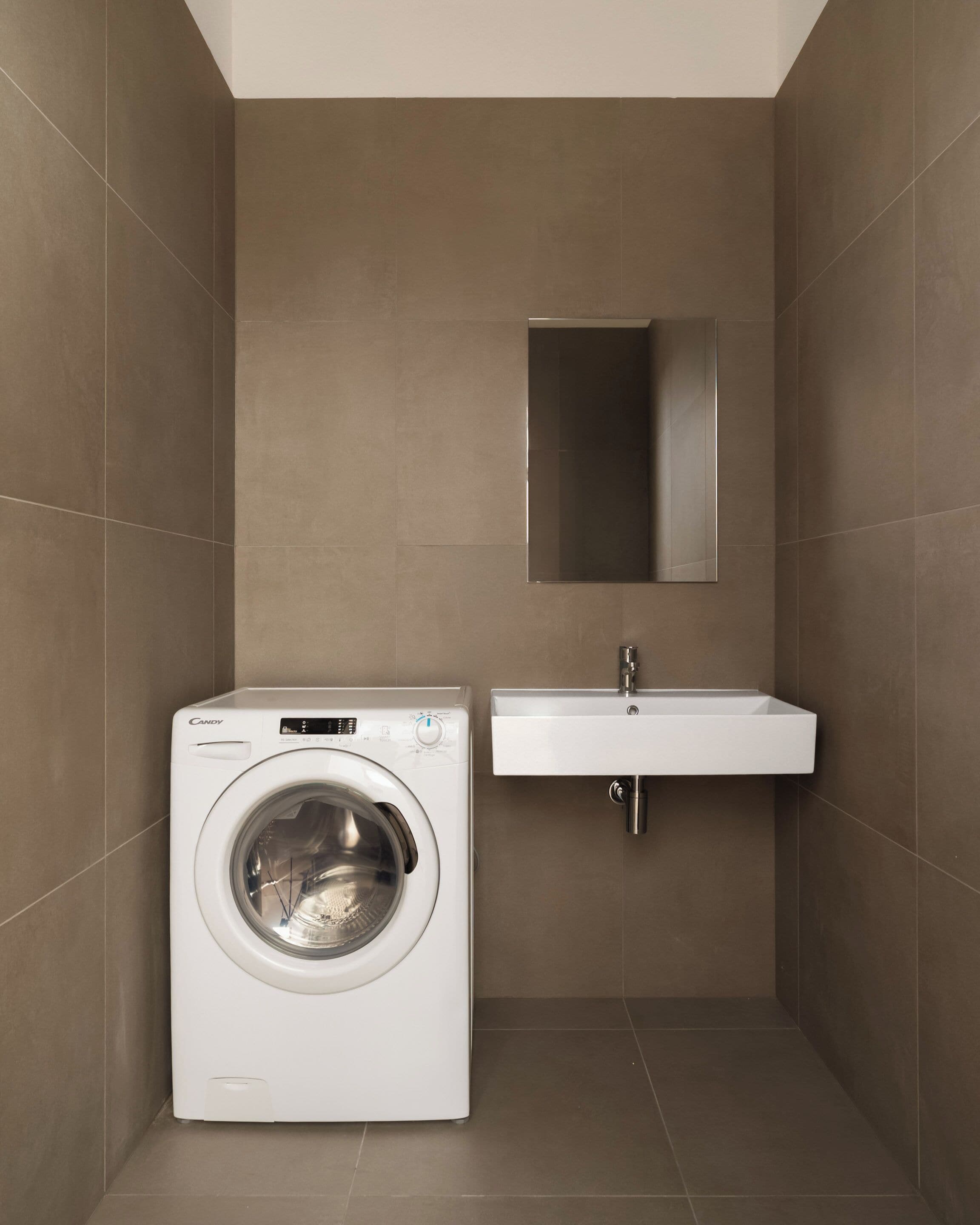 Un baño pequeño con lavadora, lavamanos y espejo.