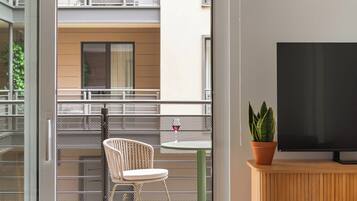 A modern living room with a sliding glass door leading to a balcony, a wooden TV stand, and a potted plant.