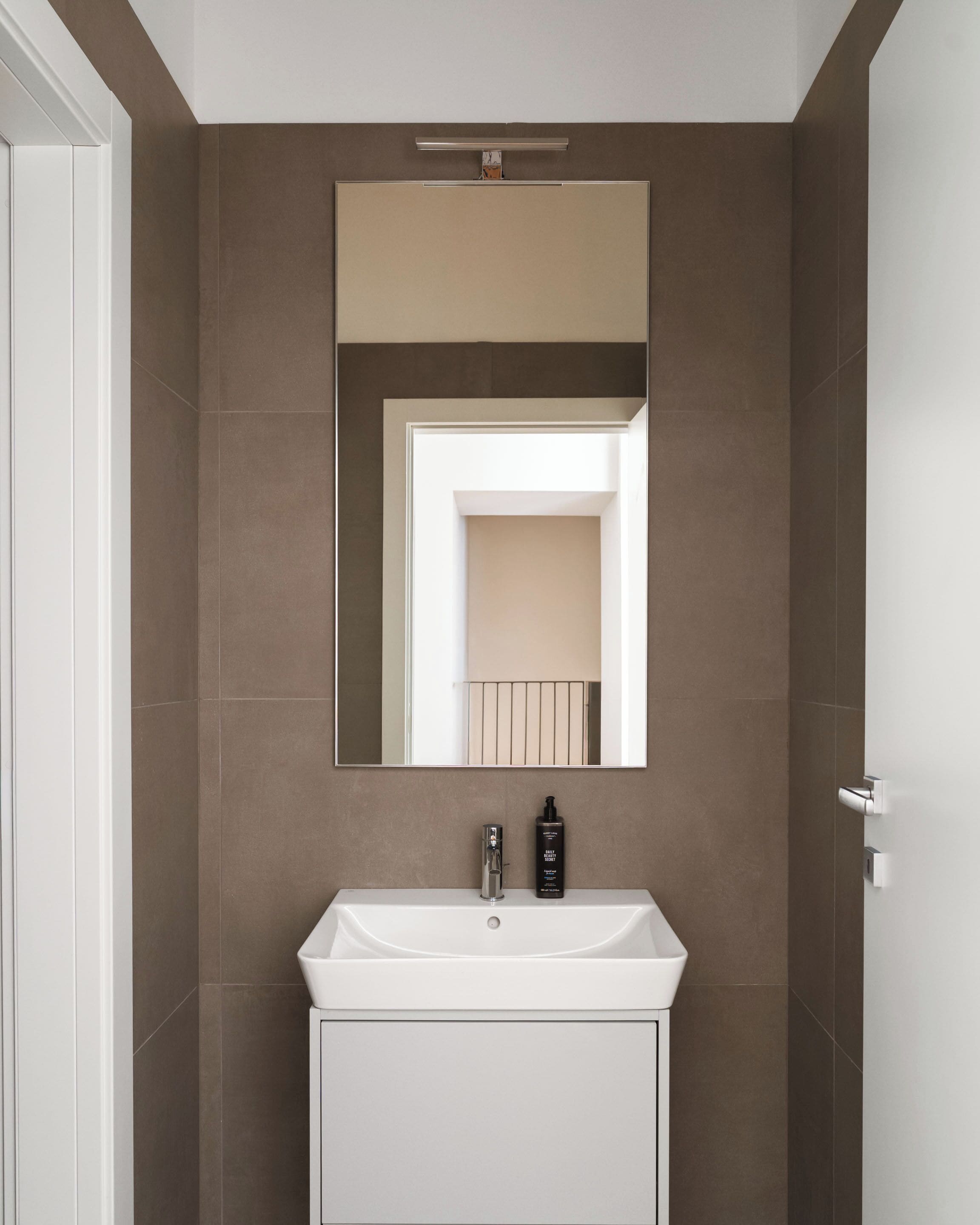 A bathroom with a white sink, a mirror, and a door.