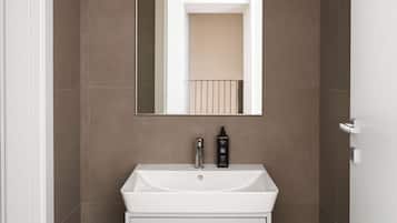 A bathroom with a white sink, a mirror, and a door.