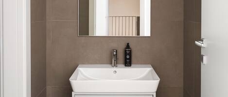 A bathroom with a white sink, a mirror, and a door.