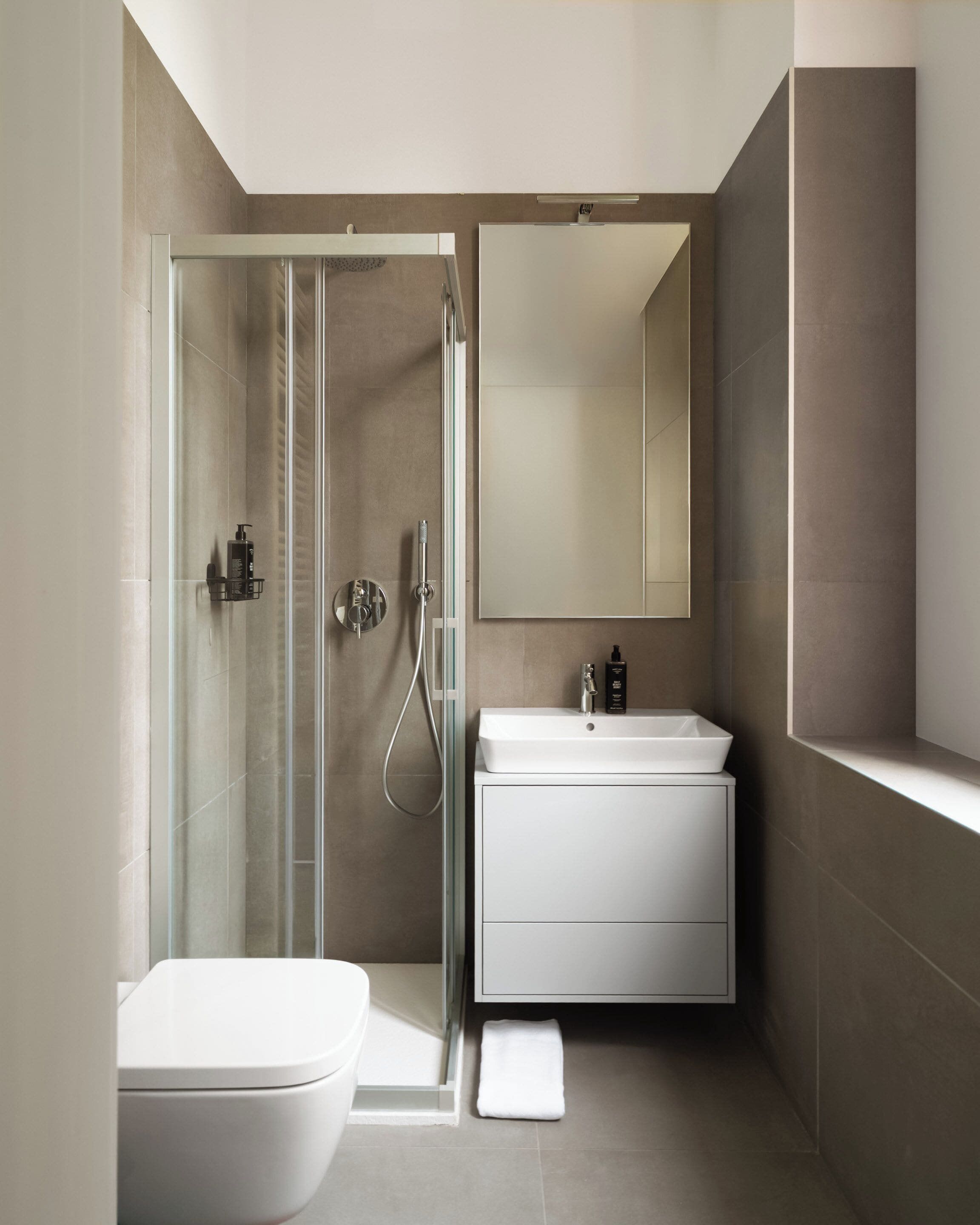 A modern bathroom with a glass-enclosed shower, a white sink, and a large mirror.