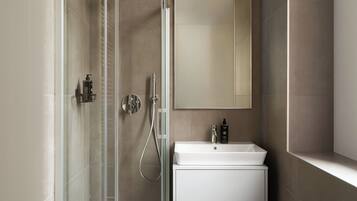 Une salle de bain moderne avec une douche à parois de verre, un lavabo blanc et un grand miroir.